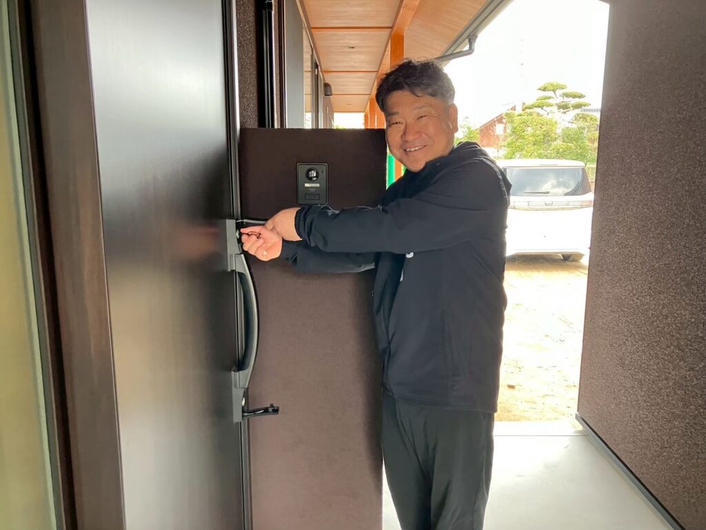 新築・注文住宅・リフォームなら鳥取県米子市の地元工務店、小田原工務店にお任せください。新築注文住宅の平屋、U様邸のお引渡し式ブログ、お引渡し式で新居キーを使って扉を開けている写真。